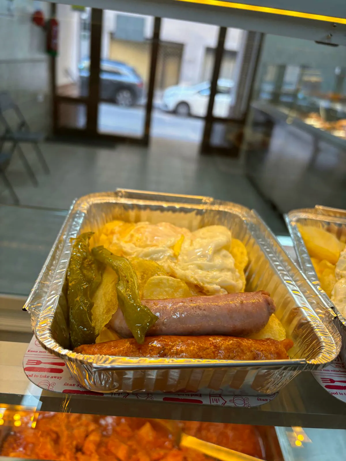 Bandeja de aluminio con huevos, patatas, pimiento y longaniza, lista para llevar