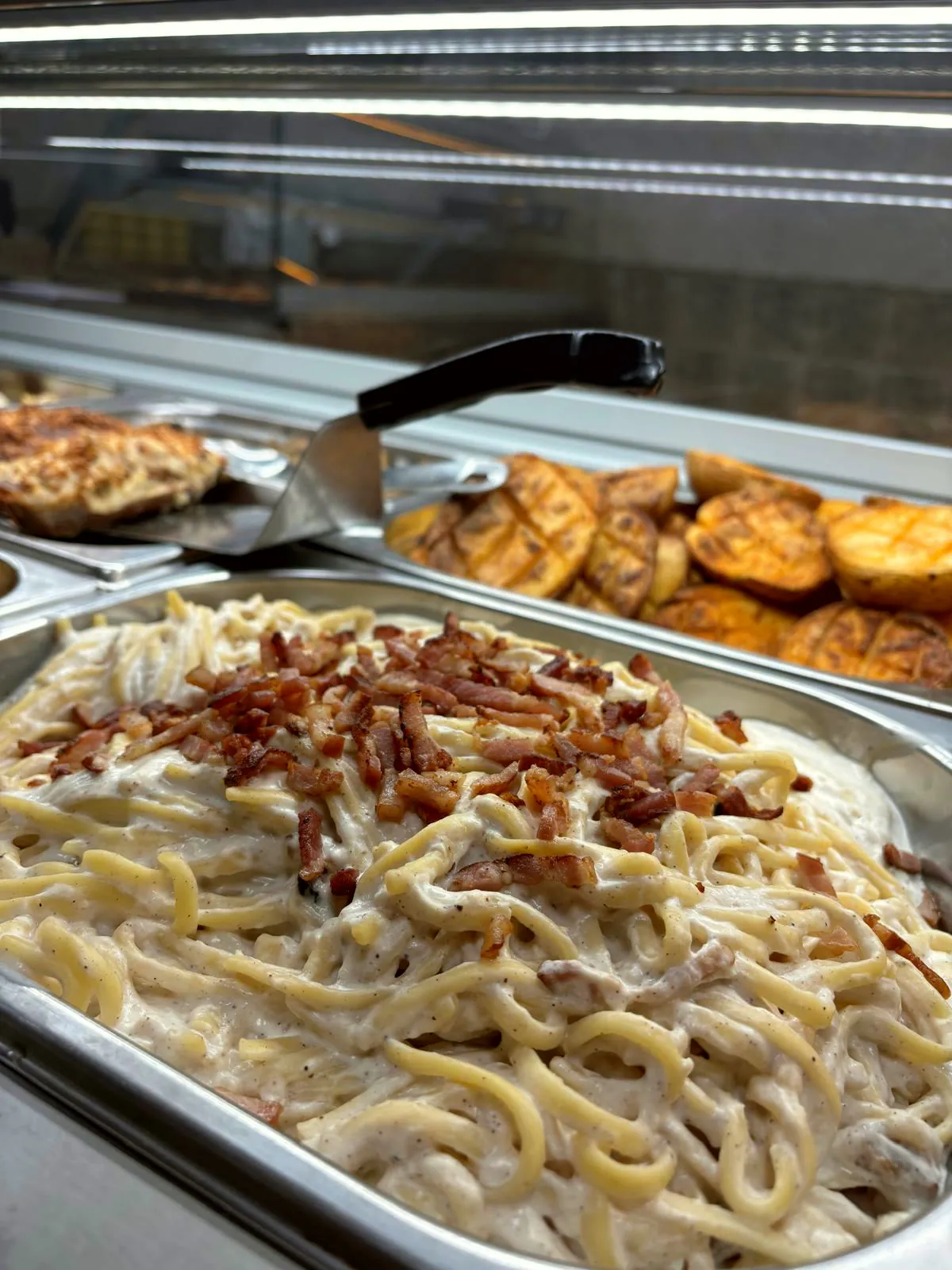 Espaguetis a la carbonara y patatas asadas en la vitrina